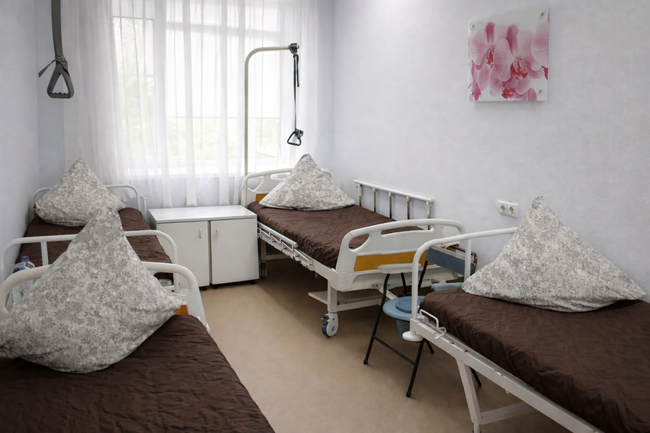 Палата стационара с двумя кроватями и прикроватными тумбочками