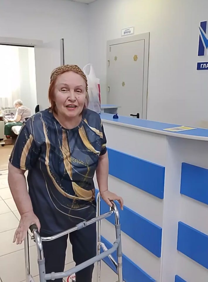 Пожилая женщина с ходунками у стойки администратора