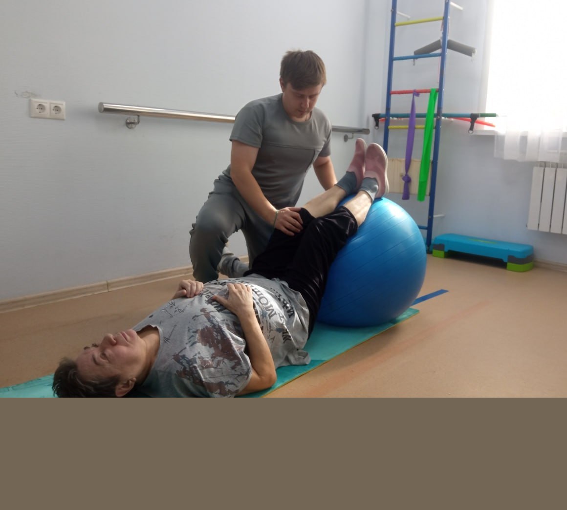 Инструктор ЛФК помогает пациенту после эндопротезирования